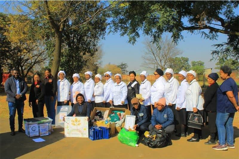 Group of volunteers and community members at outdoor charity event in South Africa.