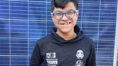 Ayaan Bhoopal stands in front of the solar panel.