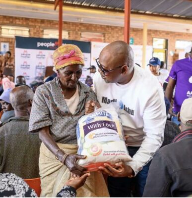 Cecil Mashawana gives a resident a food parcel.