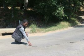 Journalist Naidine Sibanda observing the crack down the middle of the low bridge on Bridge Road in Buccleuch. Photo: Lebogang Tlou