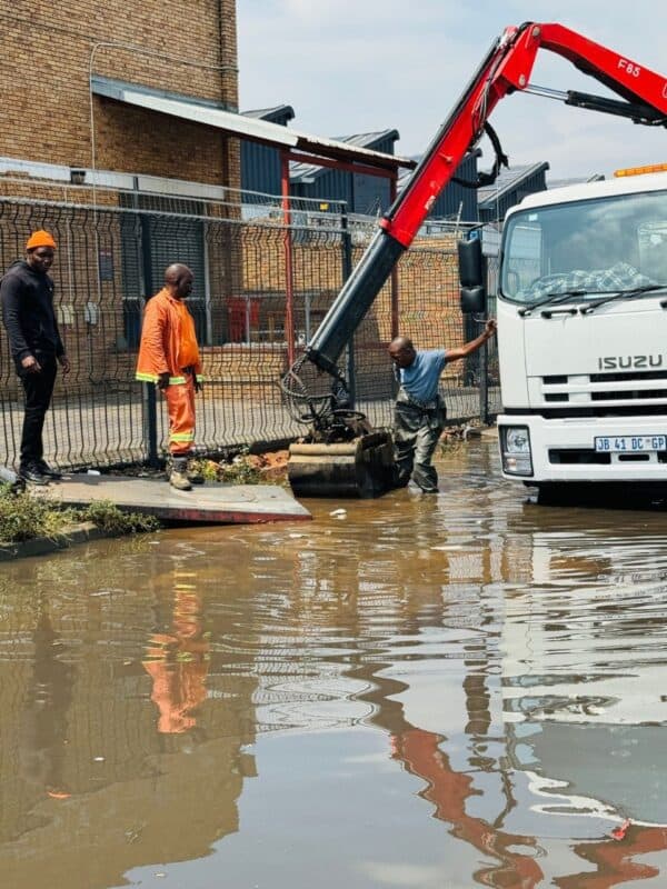 Motorists are urged to avoid Pretoria Main Road near Watt Avenue in Region E as flooding from a blocked drain causes traffic chaos, including a stranded Metrobus in the BRT lane.