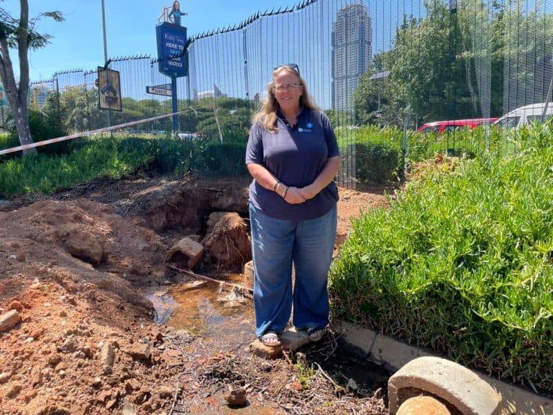 Ward 103 councillor stands next to an excavation with exposed Johannesburg Water leaking pipe at Benmore Shopping Centre. Photo: Xoliswa Zakwe