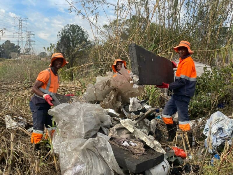 Ricardo Moyo, Duduzile Nsibande, and Evidence Vundla cleaning up Sandspruit River on Sandown on June 9, 2026. Photo: Xoliswa Zakwe