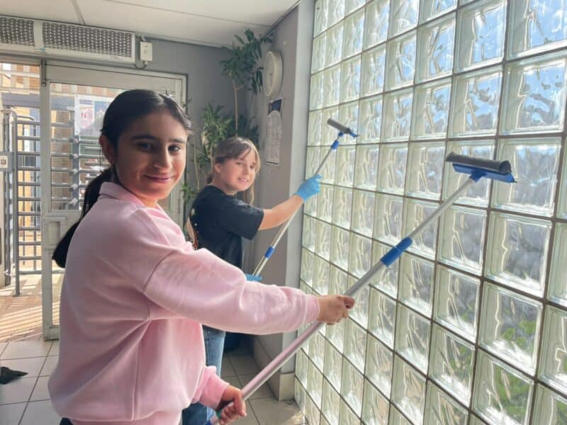 Ruhani Kapoor and Emily Johnes-Wadge help wash the windows at Sandton Police Station on July 18, 2026.