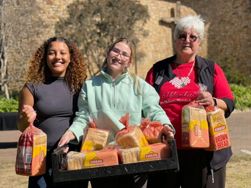 Volunteers Mia Rogers, Gabriela McKinnon and 67 Blankets ambassador Jo Corlett help spread warmth and kindness by handing out bread, biscuits and handmade knitted items to passers-by as part of the annual Mandela Day initiative. Photo: Xoliswa Zakwe
