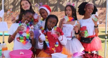 Learners dressed in colourful outfits pose behind their stall while selling drinks, sweets and other treats to fellow learners and teachers at the school’s annual Tickey Day on August 21, 2026.