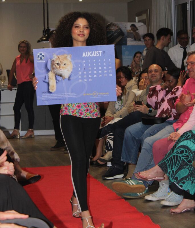 Nicky van Wyk walks the red carpet holding the August calendar page featuring Spencer during the launch at Bryanston Country Club on August 27, 2026.