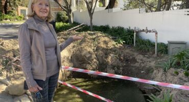 Zonia Bill points to the water-filled excavation outside La Piazza Complex on July 24, 2026.