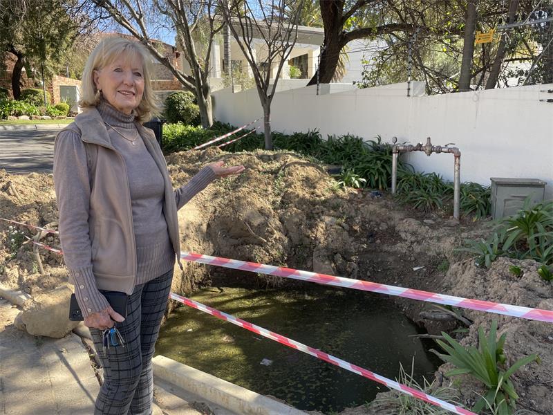 Zonia Bill points to the water-filled excavation outside La Piazza Complex on July 24, 2026.