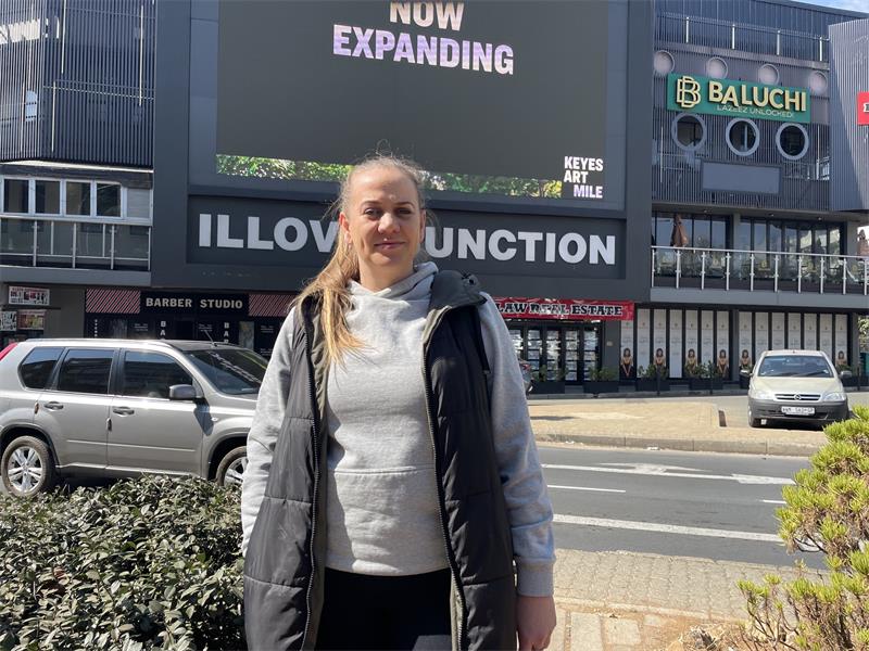 Illovo resident Helien Gous stands outside Illovo Junction, where she says the giant digital billboard has caused years of frustration for nearby residents and motorists travelling along the corner