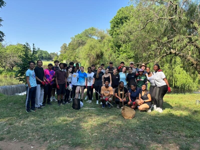 Volunteers prevent plastic pollution from travelling downstream to the ocean during a community clean-up.
