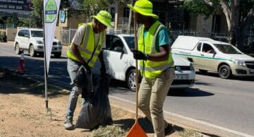 Sive Soul and Mike Ncube clear weeds along Winnie Mandela Drive during the Better Bryanston clean-up on October 23, 2026.