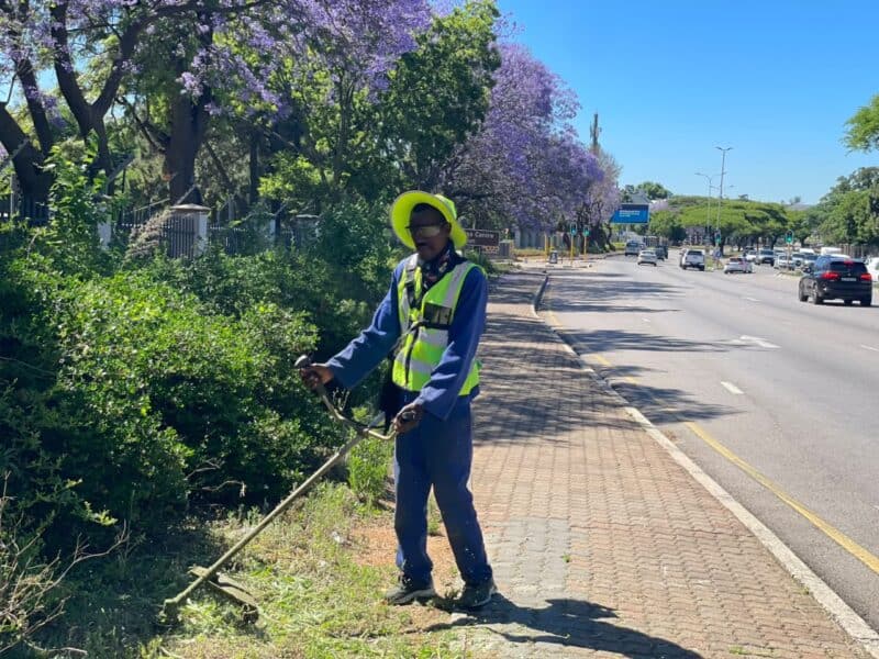 Promise Mpofu cuts the grass along Winnie Mandela Drive during the Better Bryanston clean-up on October 23, 2026.