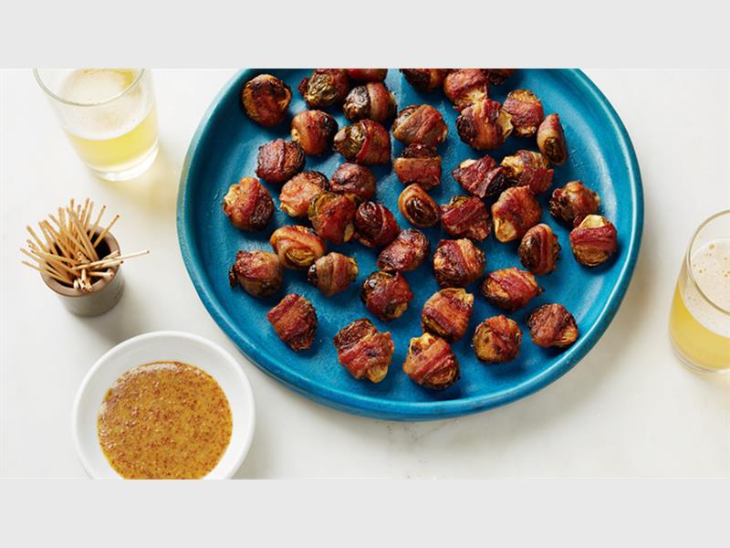BACON-WRAPPED BRUSSELS SPROUTS: Preheat the oven to 200°C. Season some brussels sprouts with salt, pepper and thyme. Wrap each sprout in a very thin slice of bacon and set these on a baking-sheet-covered wire rack in the oven. Bake them for 45 minutes, flipping them halfway through. When the bacon is crispy, remove them and let them cool. Serve with your favourite dipping sauce.