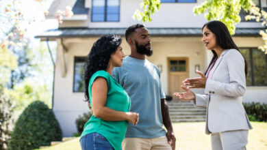 Couple meeting with real estate agent in front of home