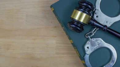 Gavel And Handcuffs On The Law Book Over The Wooden Table Background