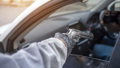 Gangster with a gun trying to rob a guy which is sitting in his car.