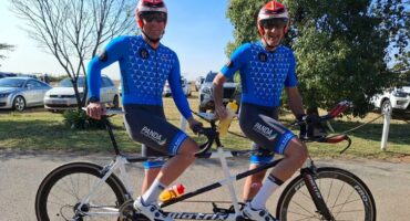 Two men in blue and white cycling outfits.