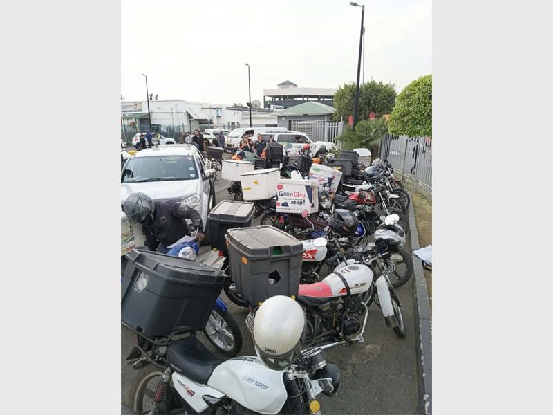 Scooters and motorcycles parked outside a commercial area in Alberton, South Africa.