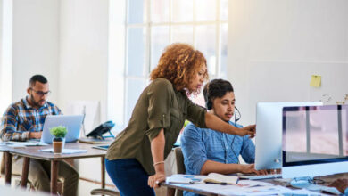 Shot of a young phone operator speaking with a coworker at his desk