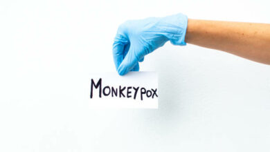 hand with blue surgical glove holding sign with the word monkeyvox