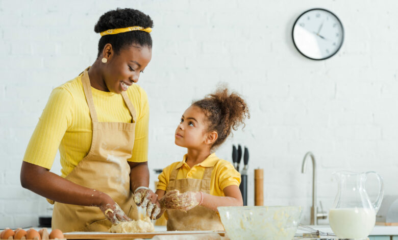 cute african american daughter looking at cheerful mother kneadi