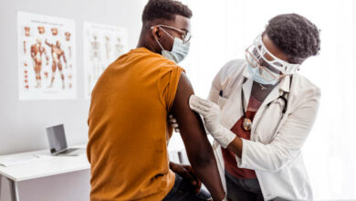 Serious man taking a vaccine from his female doctor during pandemic times.
