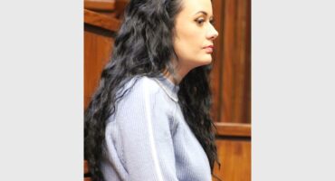A woman with long hair sitting in a courtroom.