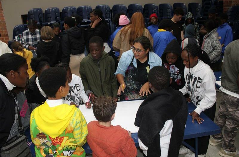 A group of children standing around a table with a woman.
