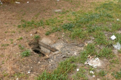 The uncovered drain where the sewage seeps from.