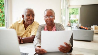Shot of a african senior couple reading document with laptop at home