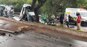Damaged vehicle involved in a serious accident with emergency responders at the scene, road debris scattered across the street.