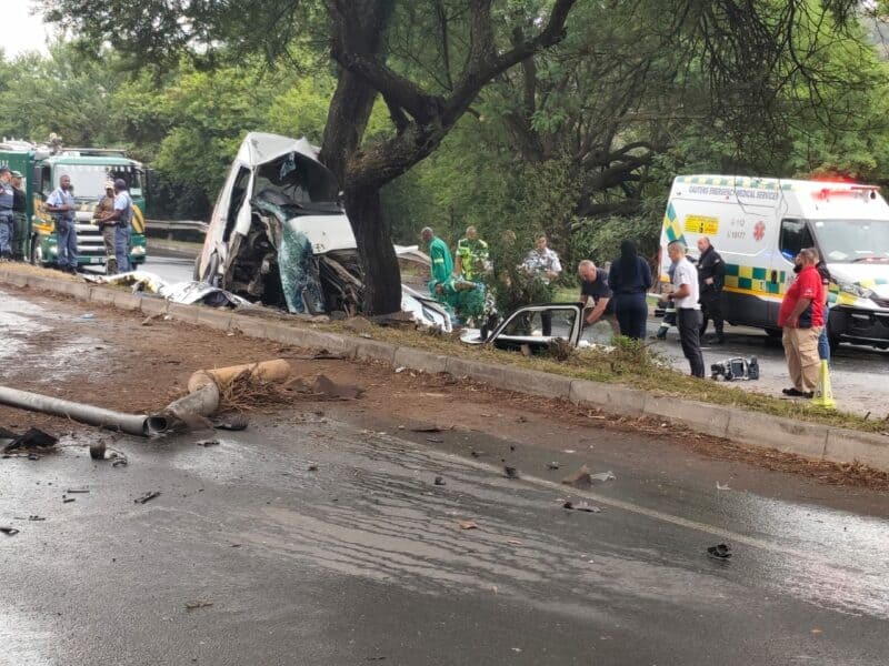 Damaged vehicle involved in a serious accident with emergency responders at the scene, road debris scattered across the street.