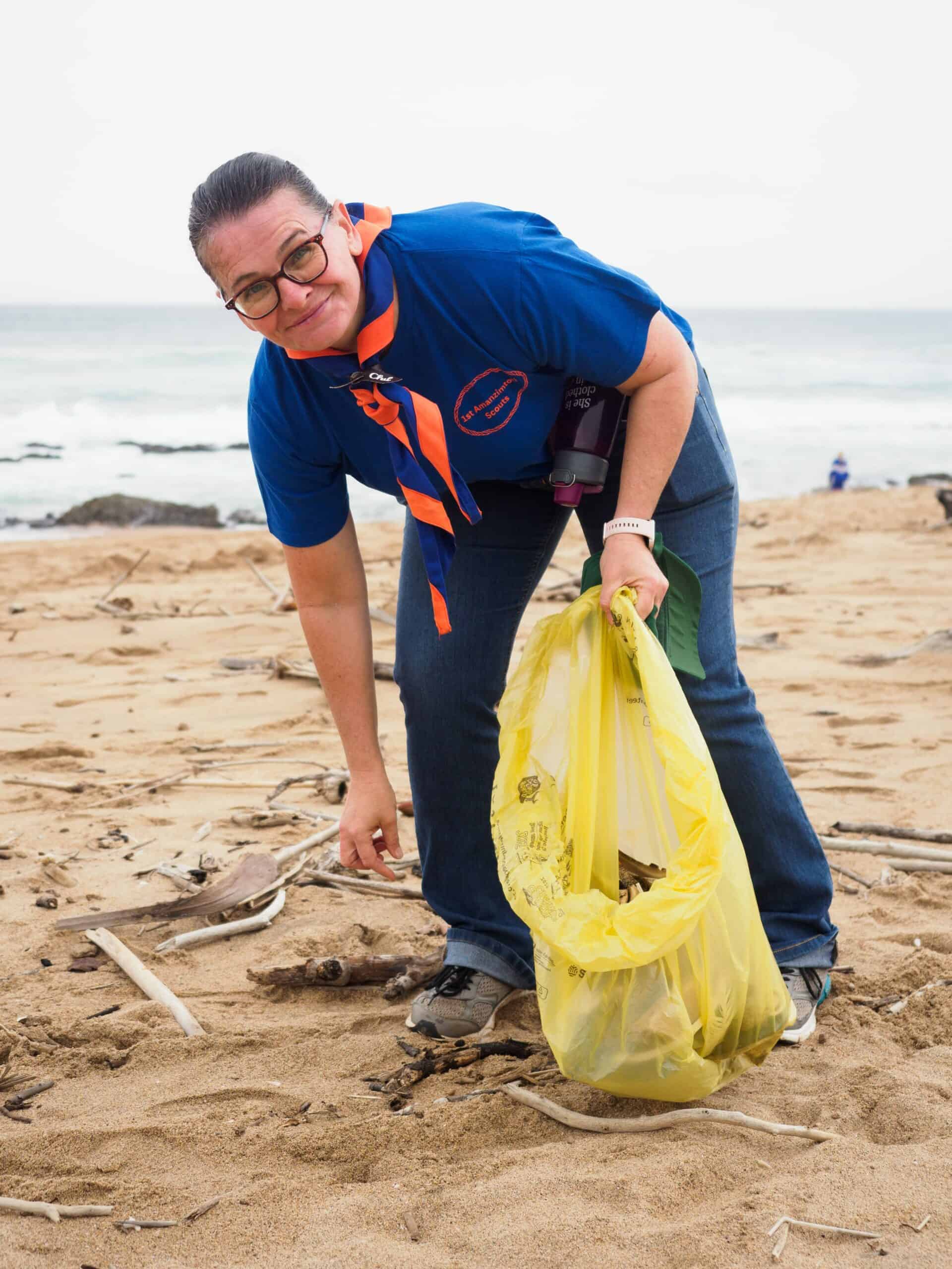 A woman cleaning on a beach.