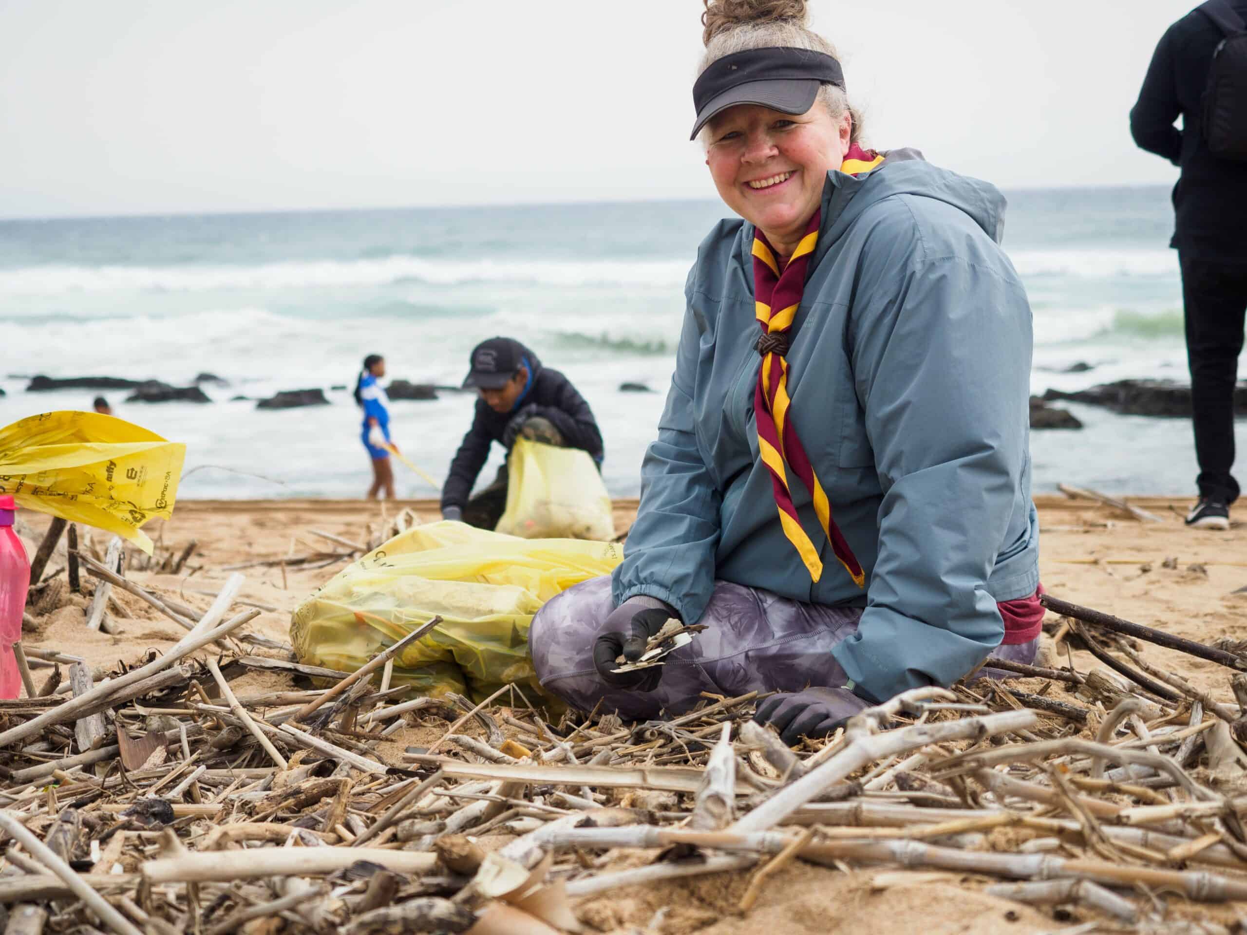 A woman cleaning up on a beach.