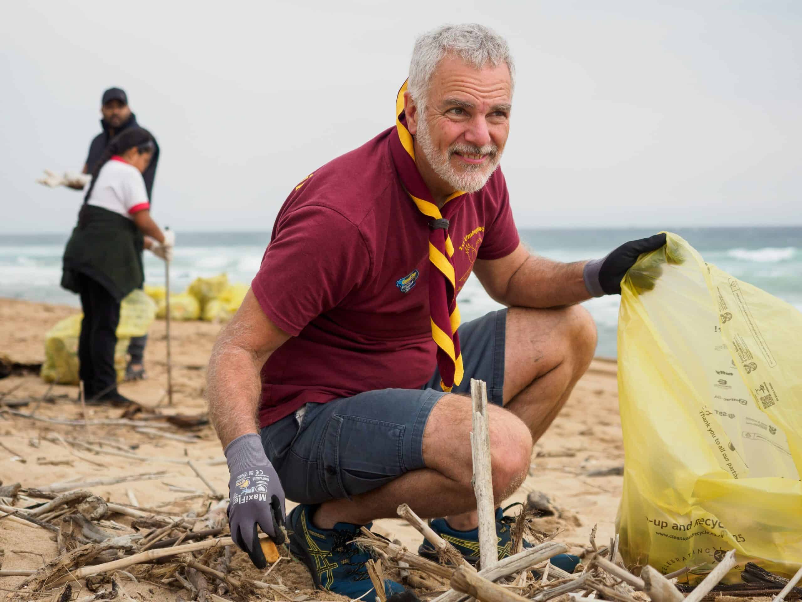 A man cleaning up on a beach.