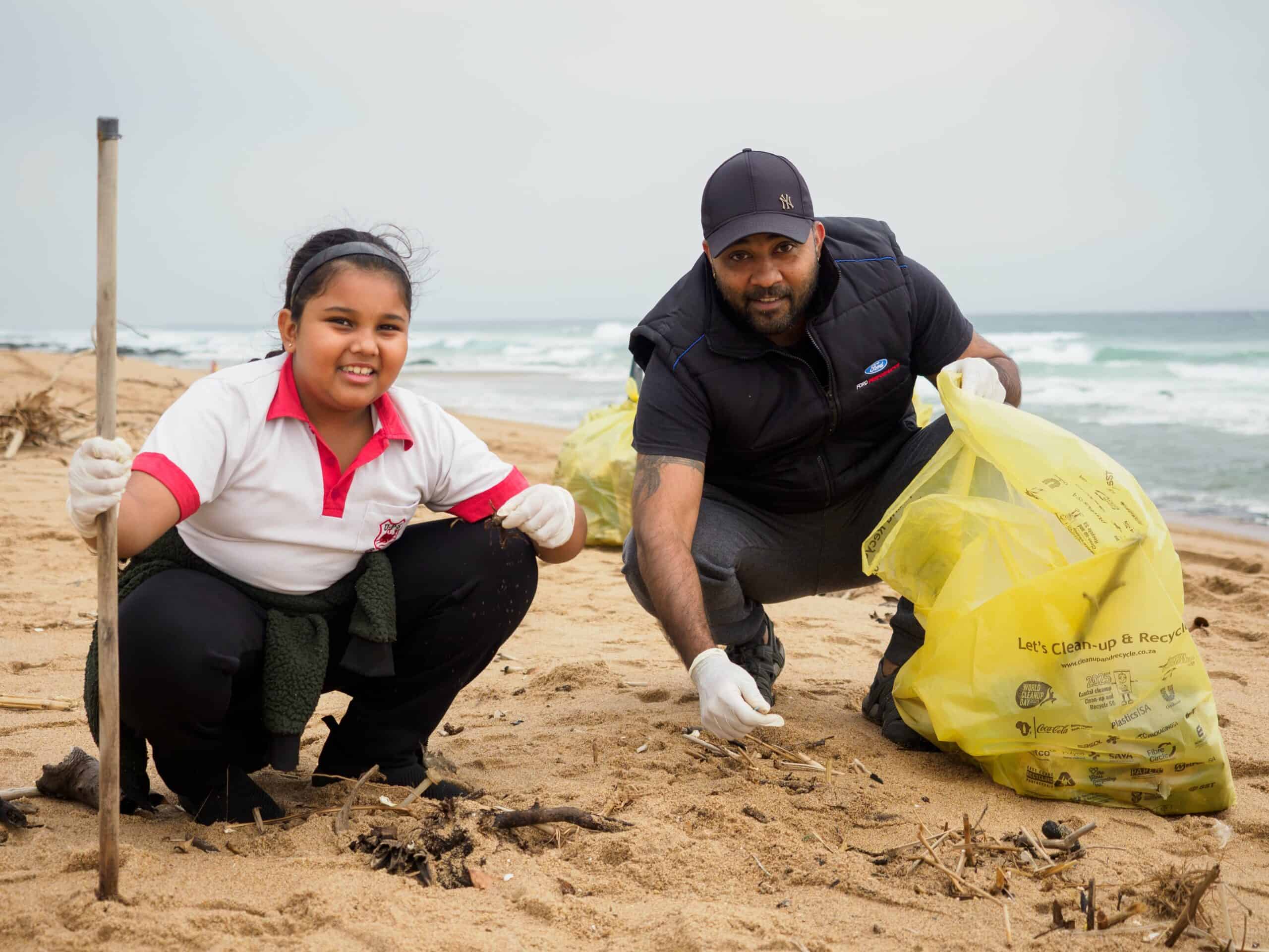 A daughter and her father cleaning up a beach.