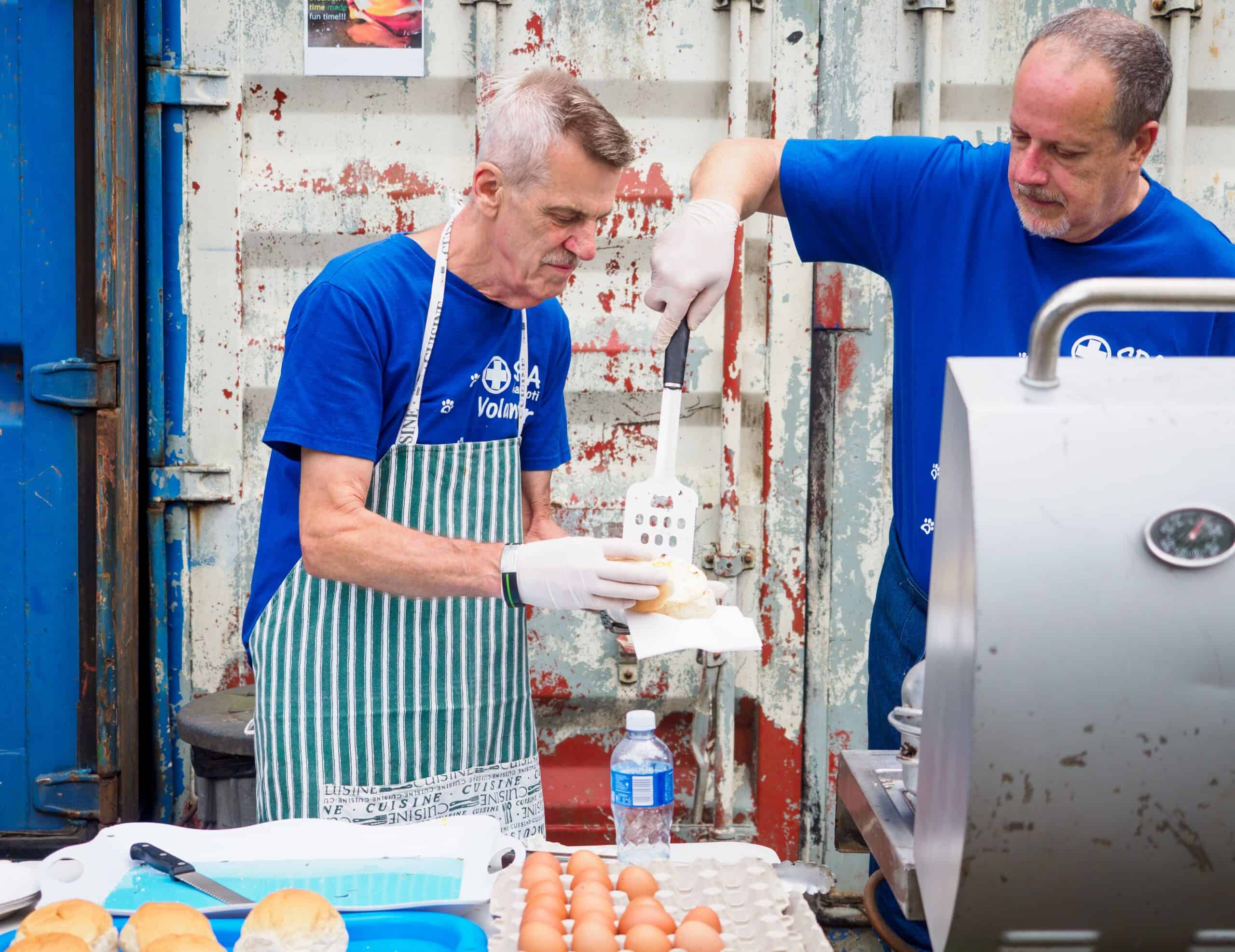 Two men manning a grill.
