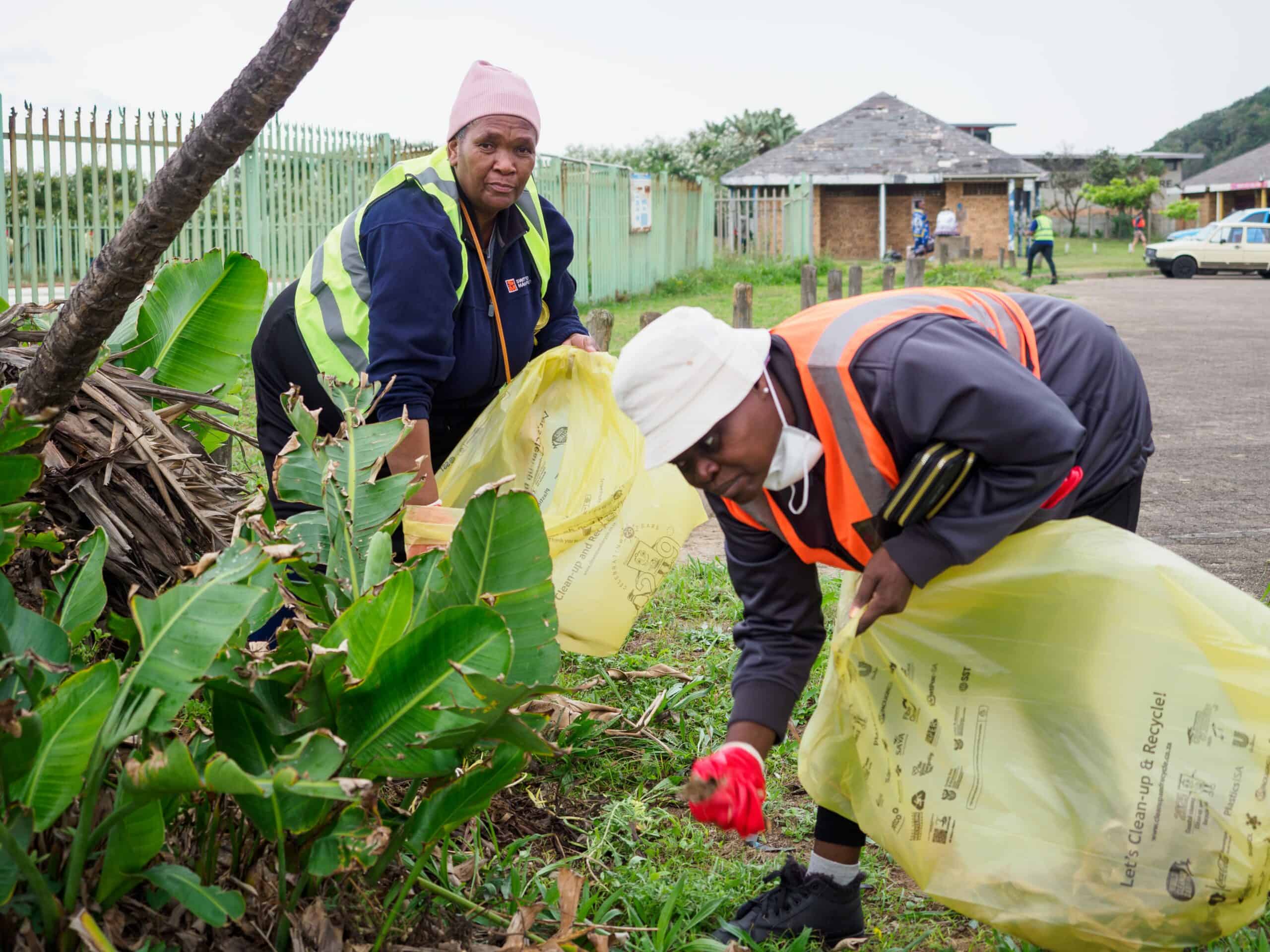 Two people cleaning up a park with a bin bag.