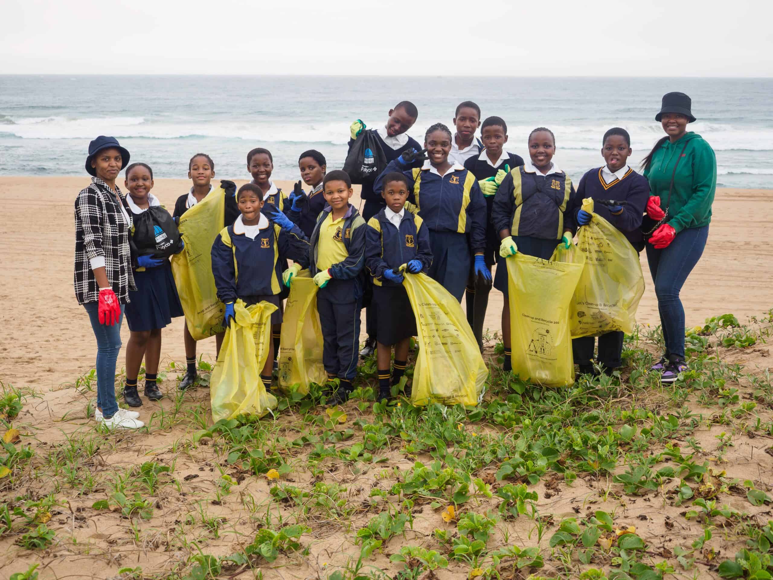 School learners and their teachers on a beach.