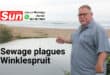 A man pointing toward a river polluted with sewage.
