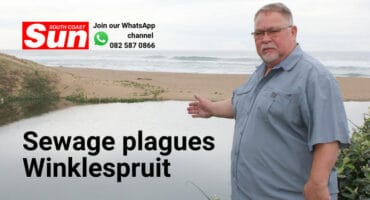 A man pointing toward a river polluted with sewage.