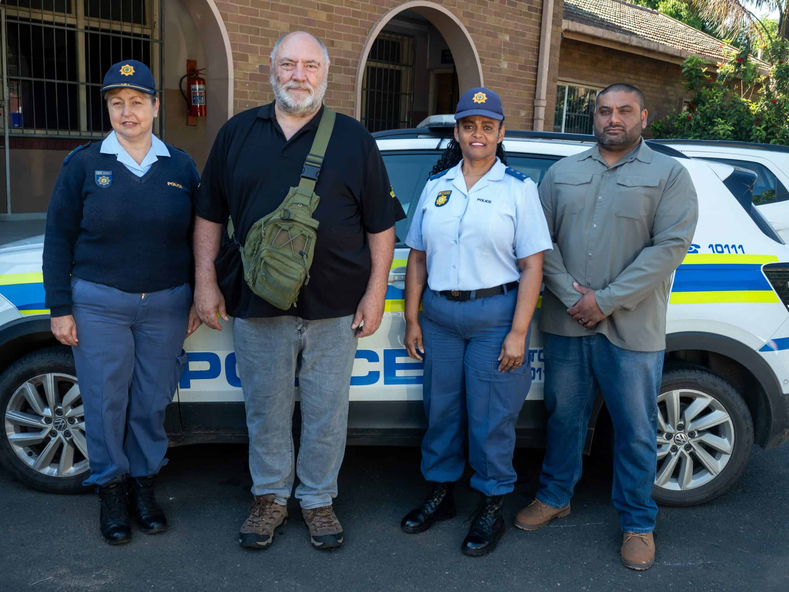A group picture in front of a police car with two female police officers.