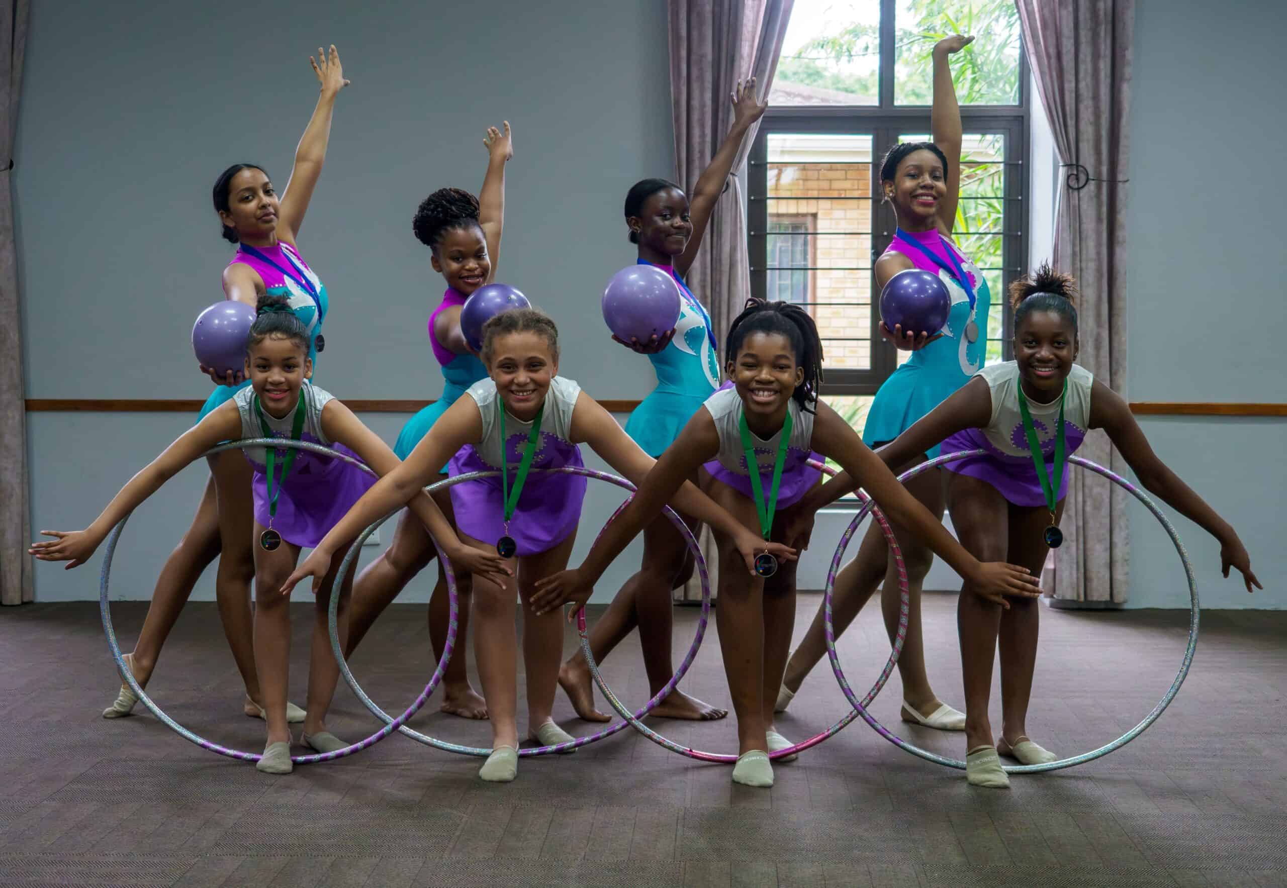 A group of rhythmic gymnasts. Four holding balls and four holding hoops.