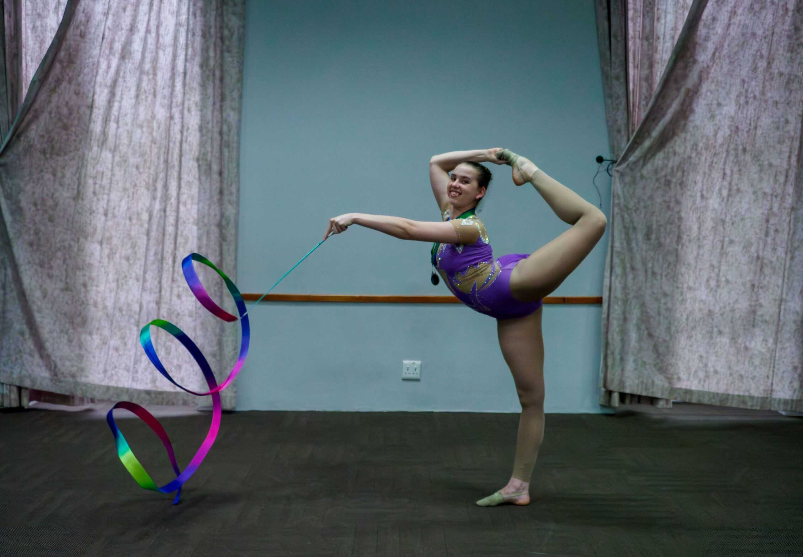 A gymnast posing and spinning a ribbon.