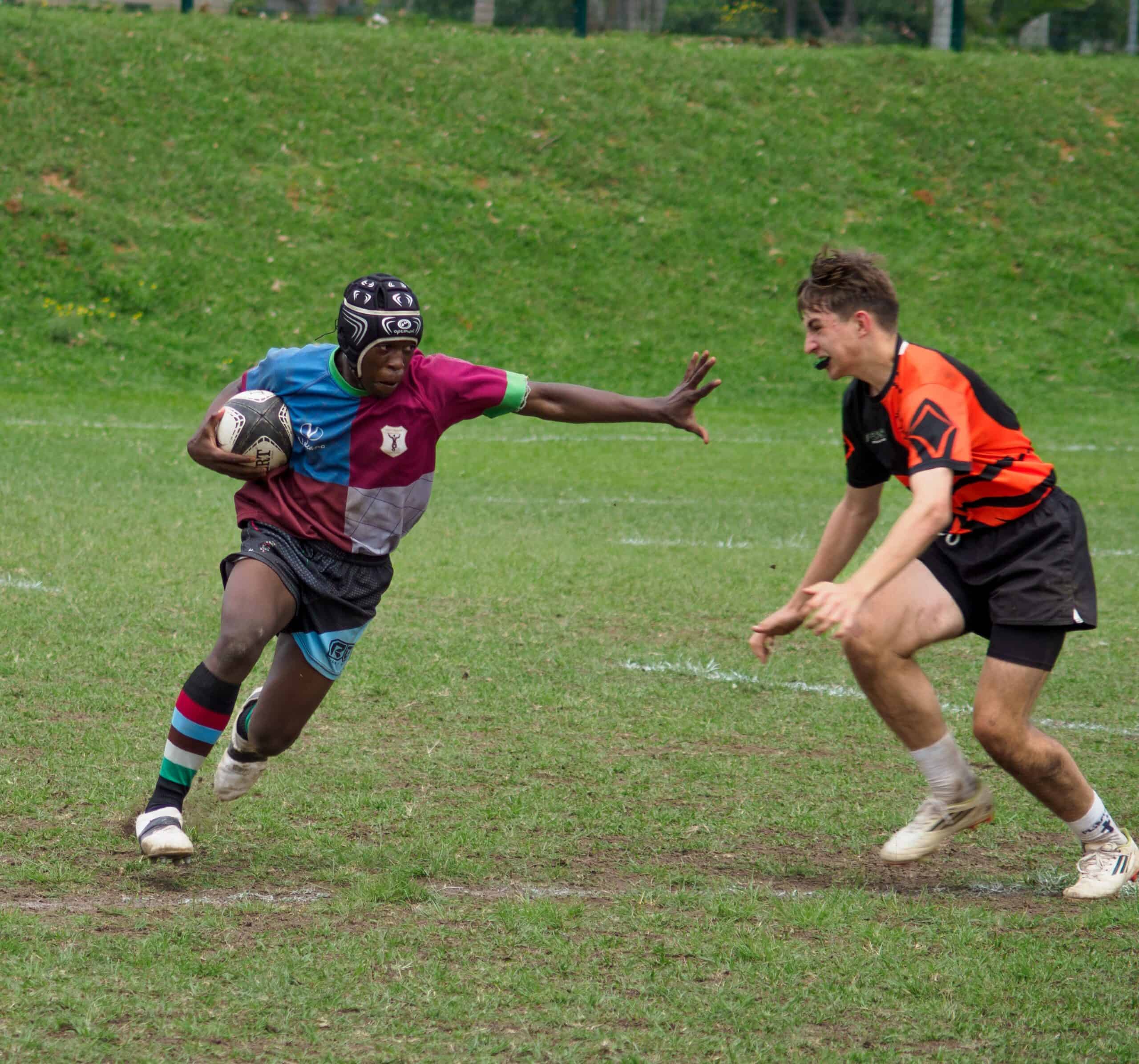 A rugby player tries to make it past a defender.
