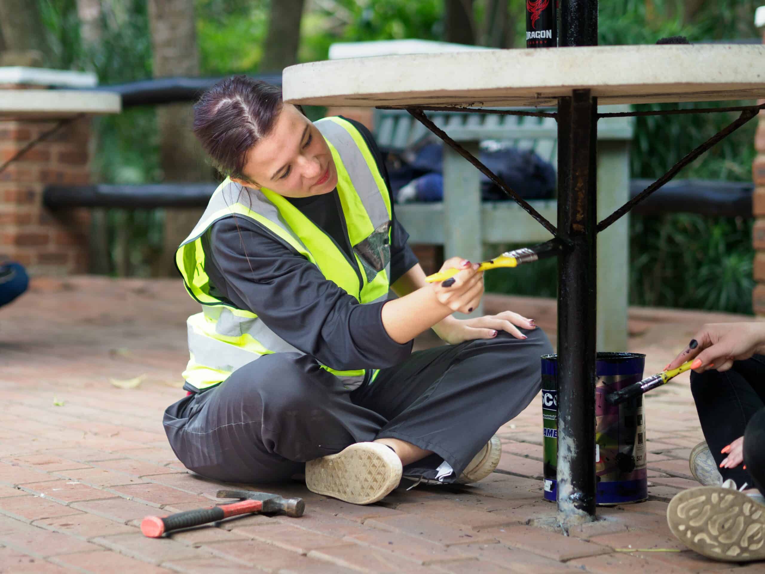 A woman painting a table stand.