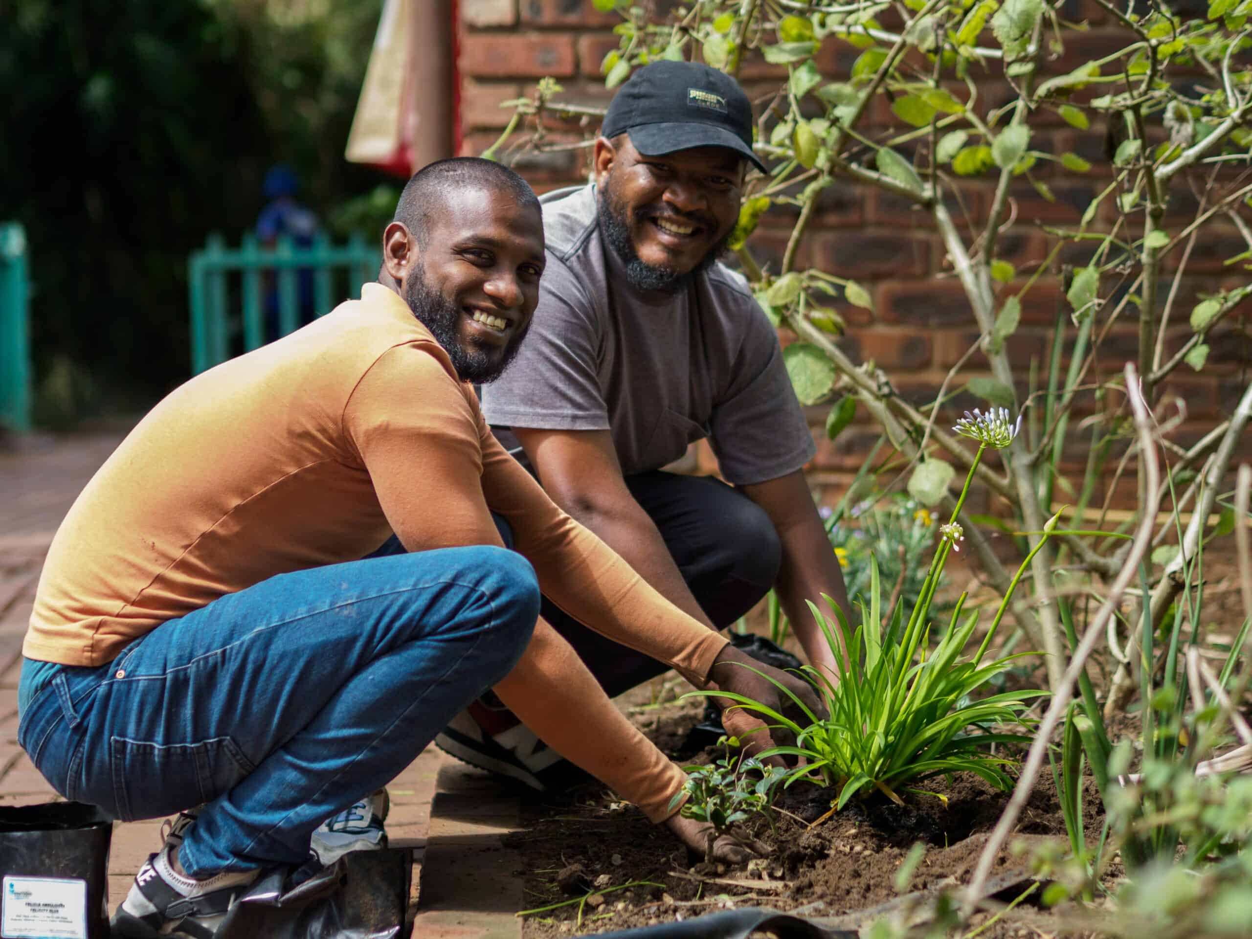 Two men planting flowers.