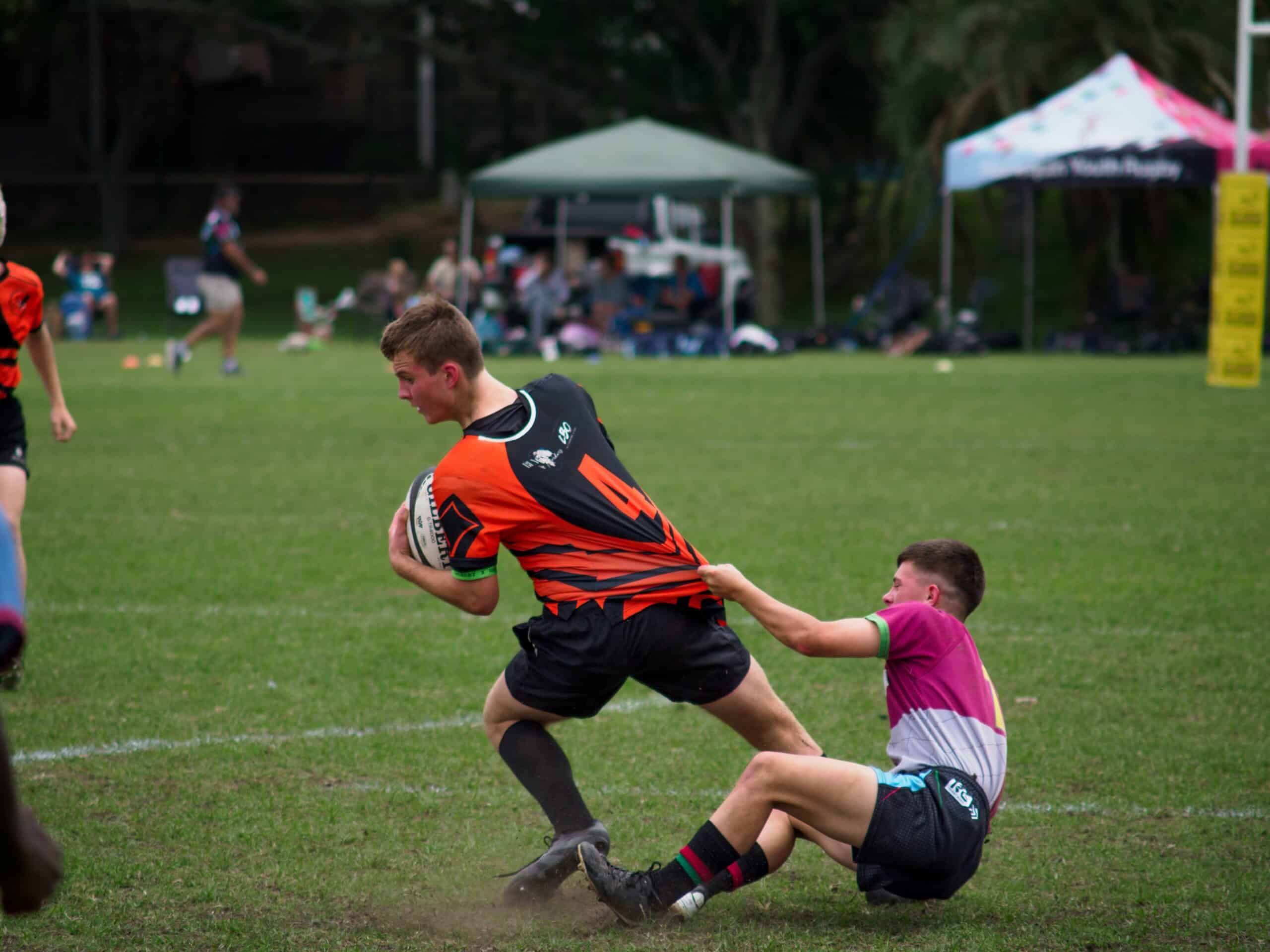 A rugby player tries to make it past a defender.