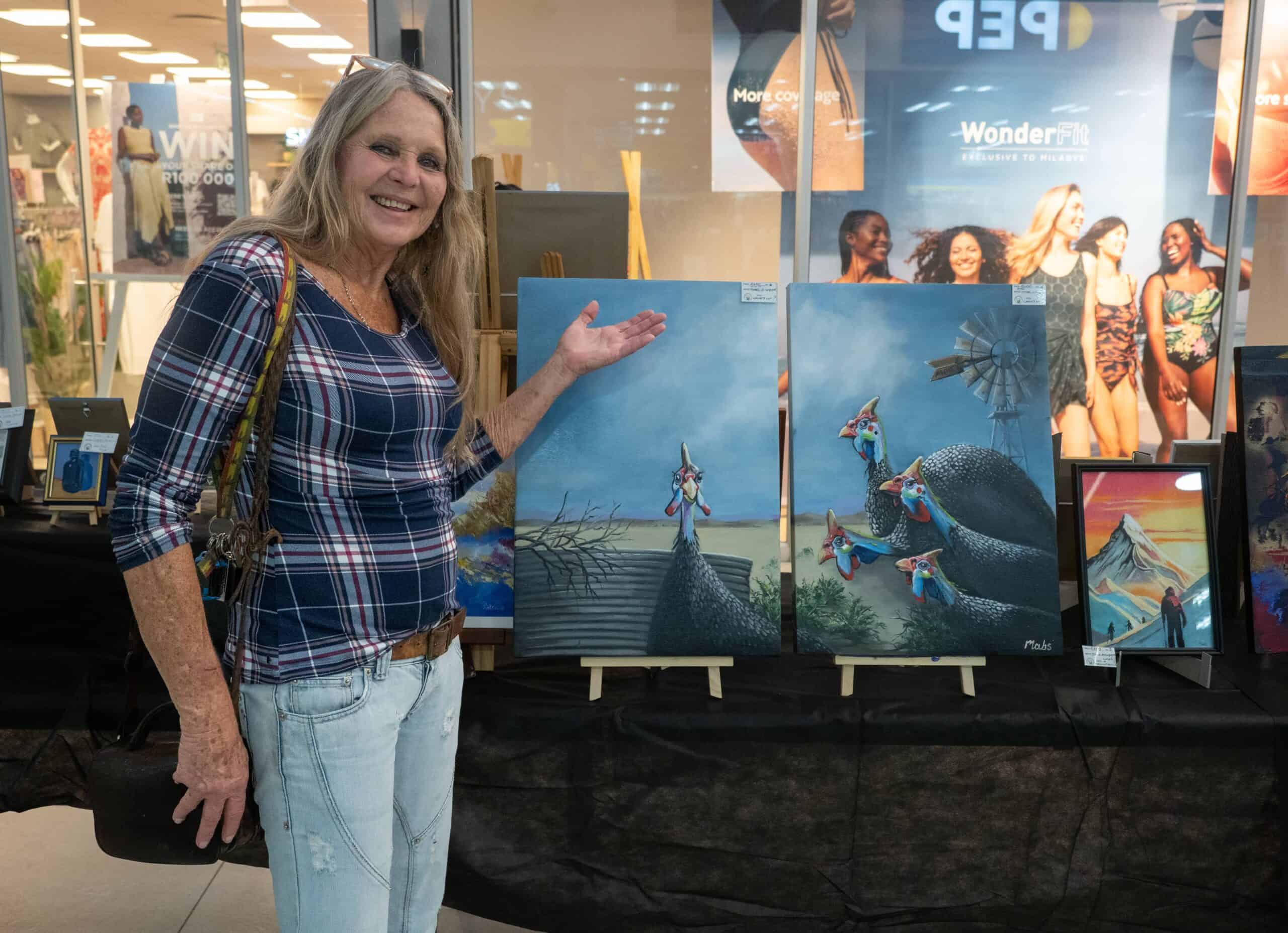 A woman showing off her twin canvas painting.